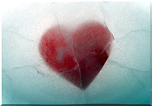 A red heart lies in the middle of ice.