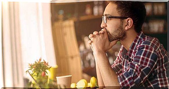 A young man sits thoughtfully at a table.