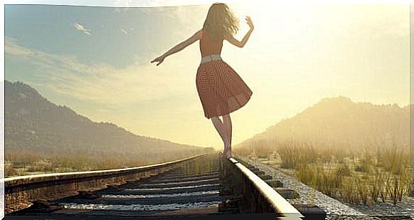 In a remote region, a woman walks on train tracks. 