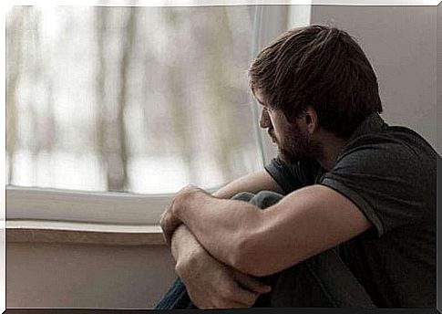 A man with apathy sits in a room and stares out the window.