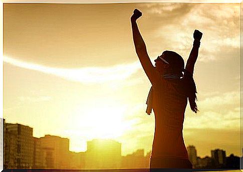 A woman in a victory pose.  She stretches her arms up.