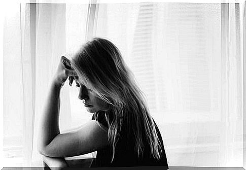 A woman has her hand on her head and looks sad and thoughtful.