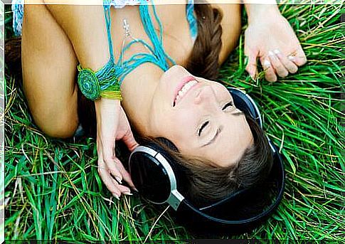 Woman lies in the grass and listens to music.