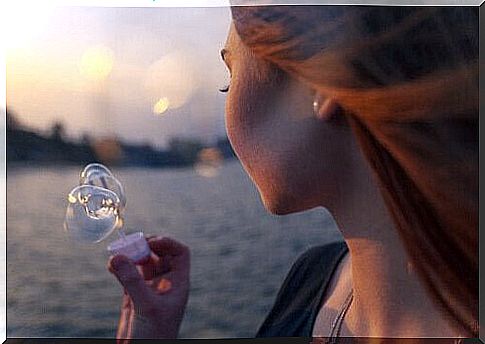 Woman makes soap bubbles by the lake