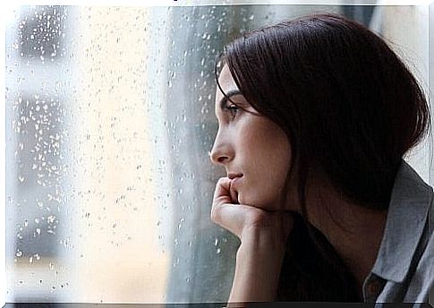 Woman looks out the window with a sad expression