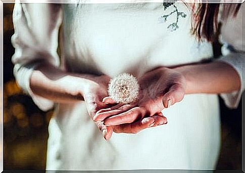 Woman carries dandelion on her hand