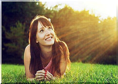 A young and happy woman is lying in the grass enjoying her life.