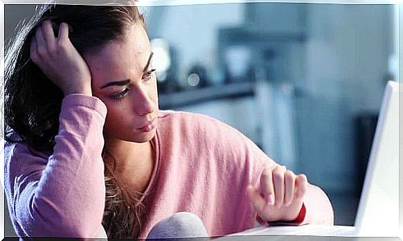 Sad teenager is sitting in front of computer