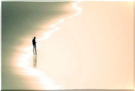 A man is standing alone on the beach.