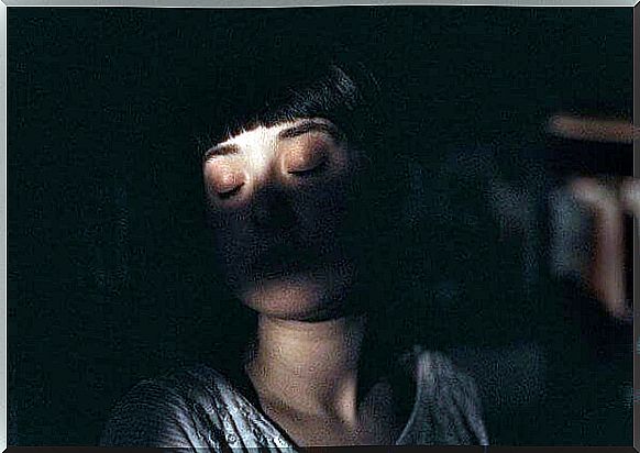 A young woman sleeps in the dark. 