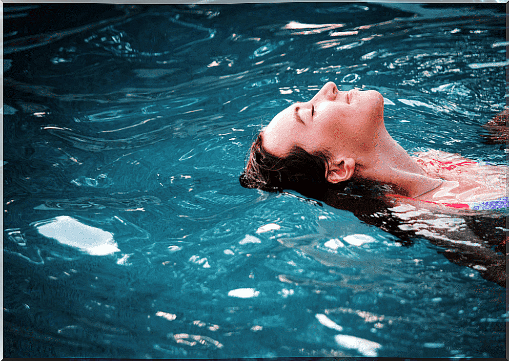 Woman floating on the surface of the water with a smile on her face