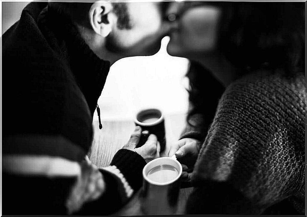 Couple kisses and drinks coffee together